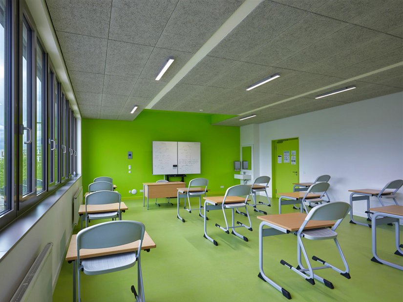 Stopniowane odcienie zieleni na podłodze i na jednej ze ścian ożywiają pomieszczenia klasowe.