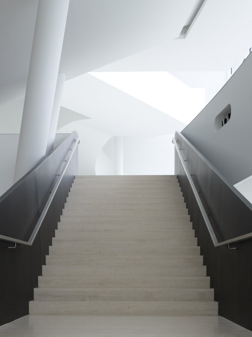Poręcze schodów stanowią ciemny akcent na wszechobecnej czystej bieli.