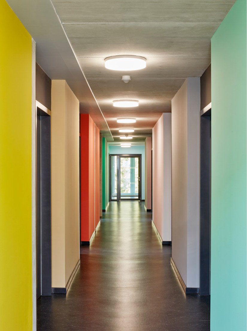 Drogi są otoczone kolorowymi szybami pomieszczeń, kierując przy tym wzrok na zieloną przestrzeń zewnętrzną lub odsuwając się w bok, aby zapewnić dostęp do pomieszczeń mieszkalnych.
Zdjęcie © Sigurd Steinprinz / ACMS Archirtekten GmbH