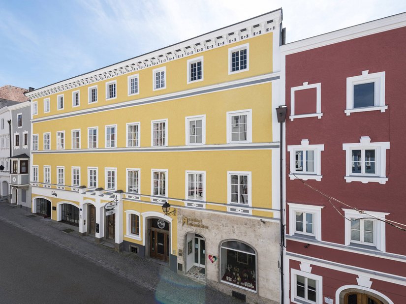 Zestawienie kolorów żółtego ochrowego z szarością i ceglaną czerwienią budynku sąsiadującego stanowi połączenie dwóch części budynku.
