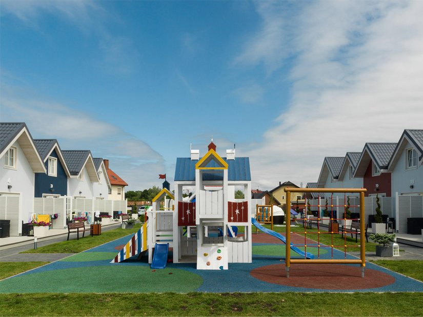 Plac zabaw między domami drewnianymi służy jako strefa rekreacyjna.